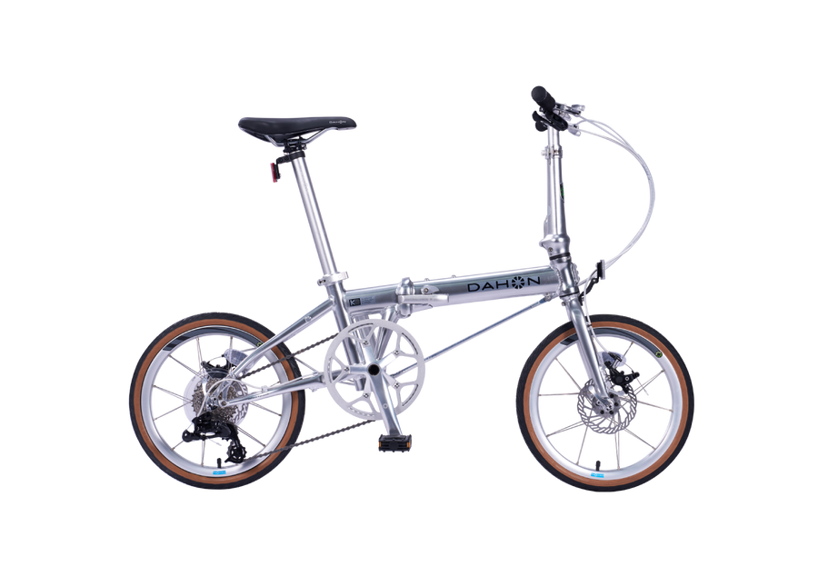 Silver DAHON K9 folding bike for urban travel with disc brakes.